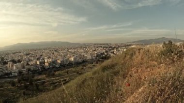Tepeden çekilen hızlandırılmış video Atina 'nın kuzey banliyölerini gösteriyor. Mavi gökyüzü ve yanından geçen bulutlarla yüksek açılı manzara. Düzenlenmemiş video.