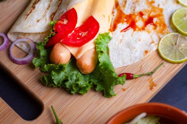 Taze domatesli, salatalı, peynirli ve soğanlı taze sosisli börek. Yan görünüm. Uzaya bak. Seçici odak