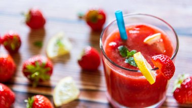 Tahta arka planda limonlu, naneli ve mavi pipetli taze çilekli smoothie. Sağlıklı yaşam tarzı kavramı.