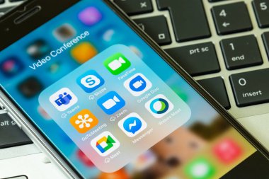 Gyor, Macaristan - 19 Mayıs 2021: Zoom 'un mobil uygulama simgeleri, Microsoft Takımları, FaceTime, Skype, Messenger, Google Duo, GoToMeeting, Google Meet ve Webex Meet iPhone' da görülmektedir. Arka planda dizüstü bilgisayar.