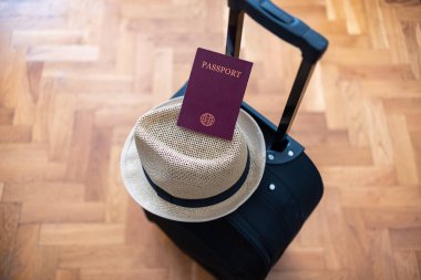 Seyahat ya da turizm konsepti. Pasaport, siyah bavul ve tahta arka planda yaz şapkası. Seçici odak.