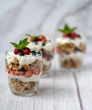 Bir bardak granola, yoğurt ve beyaz masada taze çilek. Sağlıklı kahvaltı kasesi konsepti. Yüksek kalite fotoğraf