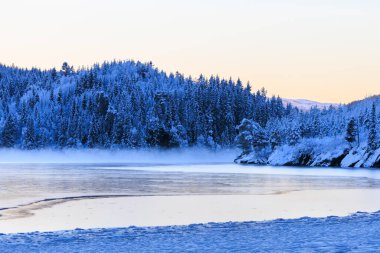 Fog on the icy lake after the sunset behind the mountains, Jonsvatnet, Norway