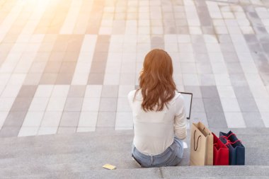 Görüntü bulanık, genç kadın alışverişe çıktıktan sonra mağazanın önünde dizüstü bilgisayardan işi kontrol ediyor. Yeni yıl arifesinde uygun fiyatlara harika ürünler almak için alışveriş fikirleri.