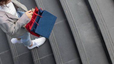 Bulanık bir görüntü, alışveriş poşeti tutan genç bir kadın bir mağazada indirimli ürünler için alışverişe çıktıktan sonra yeni yıl tatili yaklaşırken, indirimde olan bir promosyon var. alışveriş kavramı