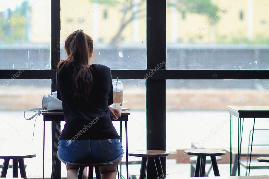 young woman brought textbook to sit in coffee shop alone to read and review knowledge in order to learn and understand lessons in  book with intention. concept of reading lessons in book to understand.