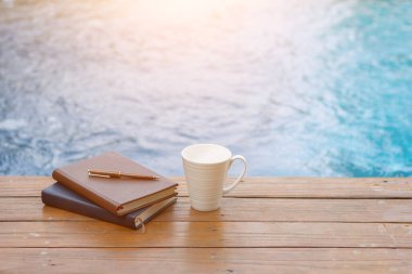 Kitaplar ve yazıtlar ahşap terasa bilardo ve beyaz kahve fincanlarının yanına yerleştirildi. İncil 'i Tanrı' ya olan inanç ve inançla anlamak için öğrenme kavramı..