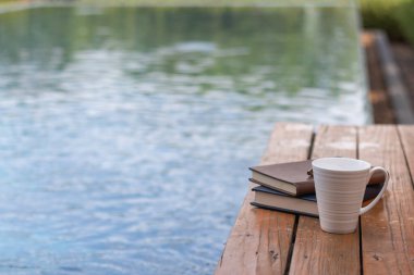 Kitaplar ve yazıtlar ahşap terasa bilardo ve beyaz kahve fincanlarının yanına yerleştirildi. İncil 'i Tanrı' ya olan inanç ve inançla anlamak için öğrenme kavramı..