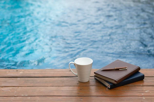 Kitaplar ve yazıtlar ahşap terasa bilardo ve beyaz kahve fincanlarının yanına yerleştirildi. İncil 'i Tanrı' ya olan inanç ve inançla anlamak için öğrenme kavramı..