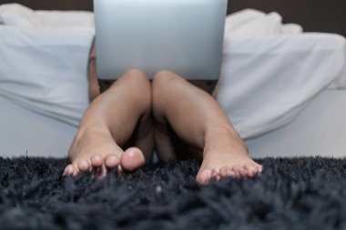 Kadın, Coronavirüs salgınından dolayı yatak odasında internet üzerinden çalışmak için dizüstü bilgisayar kullanıyor ve şirket güvende olmak ve koronavirüsün yayılmasını azaltmak için evden çalışmak istiyor..