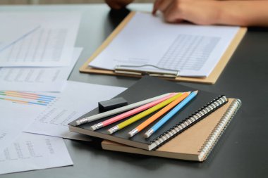 Renkli kalemler ofisteki masanın üstündeki bir deftere konur. Ofis çalışanlarının istatistiksel grafikler yazıp çizmeleri için masalara birçok boya kalemi yerleştirilir..