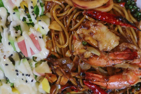 Asian woman eating spaghetti with spicy seafood sauce in a restaurant. The spicy seafood spaghetti was served in a plate and placed on the dining table as the woman ordered.