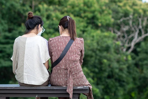 Two LGBTQ couples happily chatting on a bench by a reservoir. concept of LGBTQ couples' gender equality advocacy aims to communicate to general public to understand and accept love of LGBTQ groups.