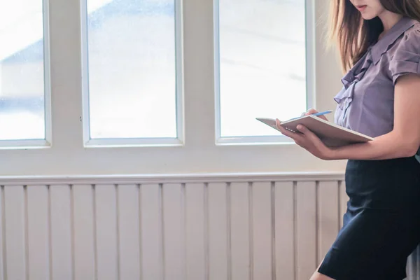 A young woman reading the Bible in the room by the window in the morning to study the teachings of God from the Bible and understand the teachings of God based on her faith in God.