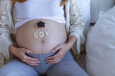 The expectant mother placed a gift and the word boy on her tummy after going for an ultrasound to determine the gender of her unborn child and prepare for the baby before it is due for delivery.