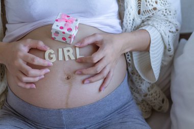 The expectant mother placed a gift box and the word girl on her stomach after going for an ultrasound to determine the gender of her unborn child to prepare. Give the baby before the due date