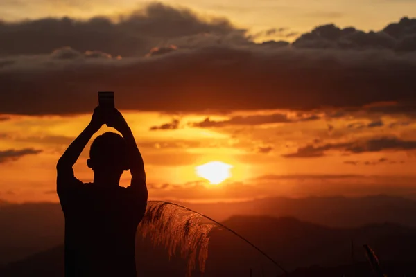 Silhouette of an old man watching beautiful lights during Twilight and watching sunset on mountains alone in loneliness. An old man is traveling and watching view of the setting sun on high mountains.