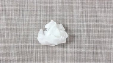 Hareket animasyonunu durdur. Kumaş kozmetik yüz maskesi bir el yardımıyla düzeltilir ve katlanır. Üst görünüm.