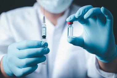Laboratuvarda elinde çocuk ya da yaşlı yetişkinler için sıvı aşı bulunan bir şırınga tutan doktor ya da bilim adamı, covid-19 Corona virüsüne karşı kavramsal mücadele, kavram: hastalıklar, tıbbi bakım, bilim.