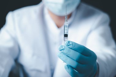 Laboratuvarda elinde çocuk ya da yaşlı yetişkinler için sıvı aşı bulunan bir şırınga tutan doktor ya da bilim adamı, covid-19 Corona virüsüne karşı kavramsal mücadele, kavram: hastalıklar, tıbbi bakım, bilim.