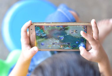 Asyalı çocuk Mobil Efsaneler oynuyor, Bang Bang oyunu. Ekran zamanı kavramı.