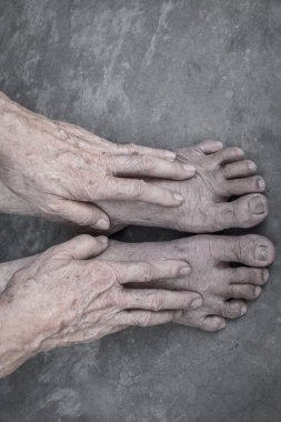 Asyalı yaşlı adam elleri ve ayakları. Ortak sağlık ve bakım kavramı ve yaşlanan deri kavramı. Somut arka planda izole edilmiş.