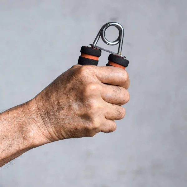 Hand of Southeast asian, Chinese old man gripping hand exercise gripper.