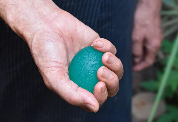 Southeast asian, Chinese old man gripping hand exercise elastic ball.