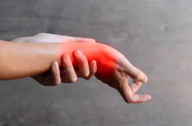 Asyalı genç adamın bilek eklemi ve eli iltihaplanmış. Eklem ağrısı ve el sorunları kavramı.