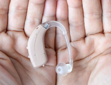 Asyalı yaşlı kadının kulağında işitme cihazı var. Sağırlık sorunu var..