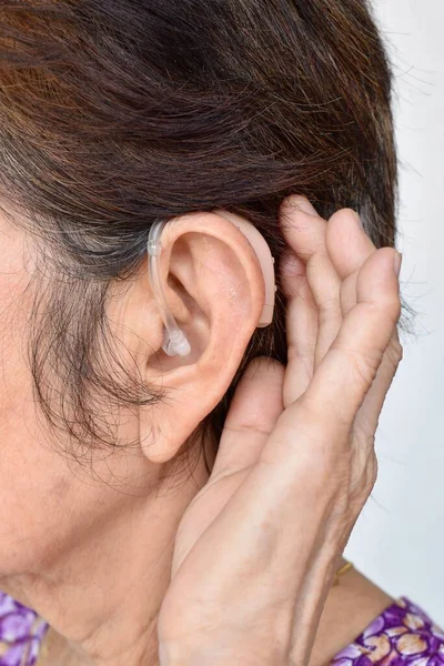 Electronic hearing aid device in the ear of Asian old woman with total deafness.