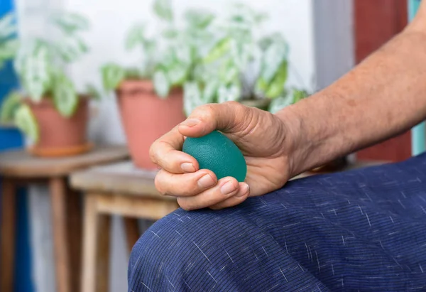 Southeast asian, Chinese old man gripping hand exercise elastic ball.