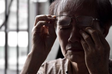 Partial silhouette image of Asian elder man rubbing his eye. Concept of eye pain, strain or itchy eyelid.