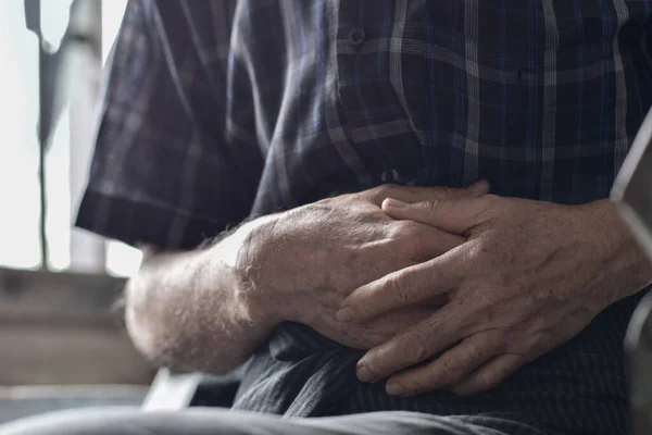 Asian elder man suffering from abdominal pain. It can be caused by stomach ache, enteritis, colitis, appendicitis, hepatitis, pancreatitis, food poisoning, etc.