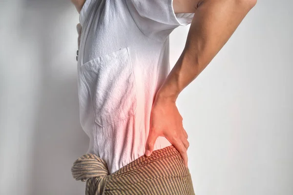 Asian young man suffering from back and loin pain. It can be caused by renal stone.