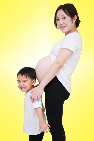 孕妇的画像 她站在工作室里笑着 儿子在黄色的背景上 有一条剪路 — 图库照片