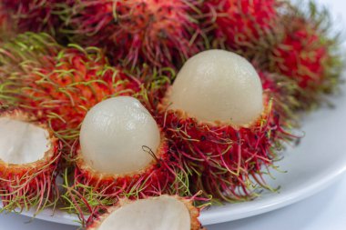 Soyulmuş kırmızı kürklü Rambutan ve beyaz bir tabağa konmuş tatlı bir tadı var, Tayland meyvesi.
