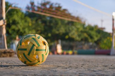 Çimento zemininde plastik top ve bulanık arka plan ve kopyalama alanı. Sepak Takraw top yakın plan sarı rattan top sporu