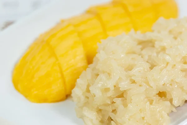 Mango sticky rice in a white dish is a food that has a sweet taste.