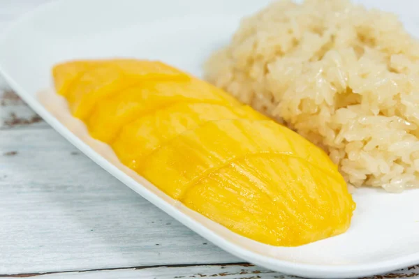 plate of mango sticky rice with mango slices cut into pieces, arranged on a plate, and close up