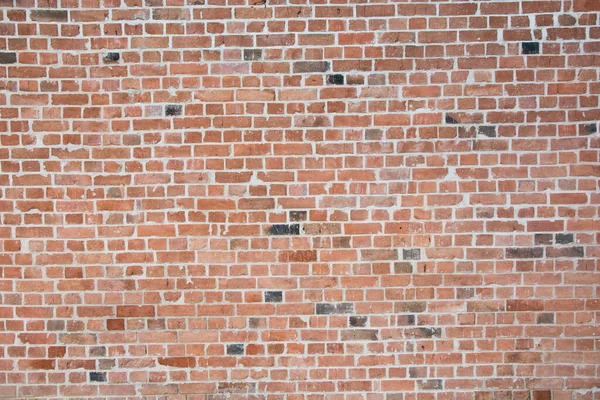 Old vintage wall with many red bricks, and some black bricks