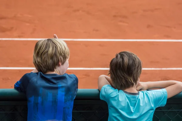 Dos Niños Mirando Hacia Atrás Viendo Partido Tenis Una Cancha Imagen de archivo