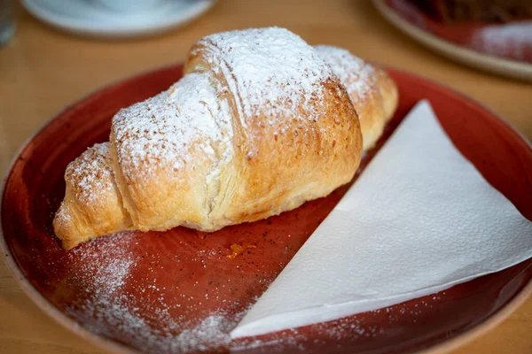 Croissant Manteiga Francês Coberto Com Açúcar Uma Placa Vermelha Lado — Fotografia de Stock