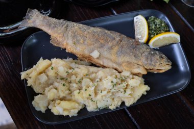 Kızarmış alabalık, yanında patates püresi ve taze salata.