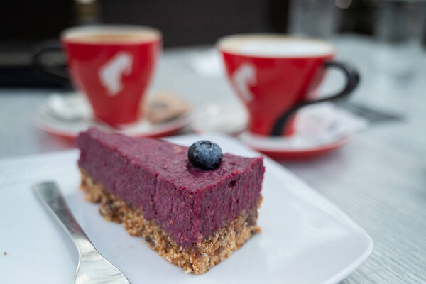 Кусок словенского черничного пирога, подается с чашками кофе