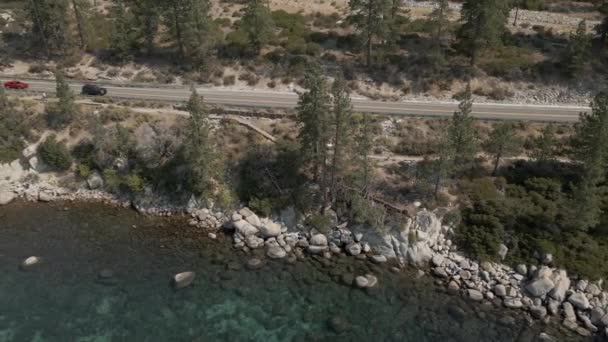 Mountain road along crystal clear lake cinematic footage — Stock video