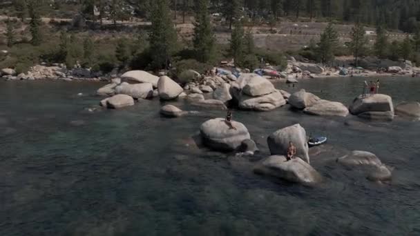 Młoda para relaksująca się na skałach jeziora — Wideo stockowe