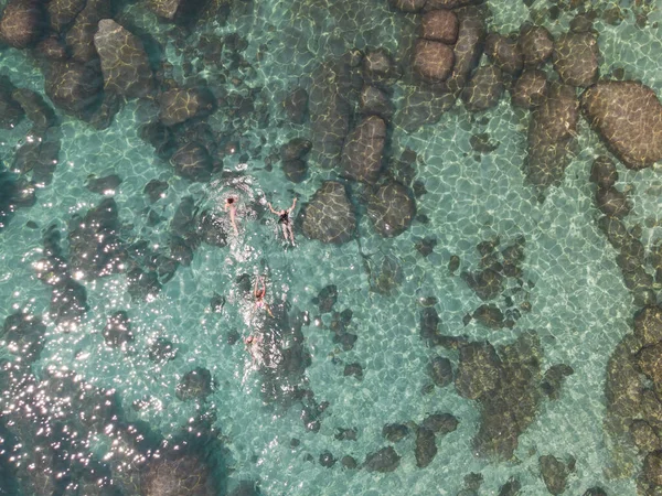 Crystal clear Lake Tahoe rocky shoreline. Ladies relaxing in the crystal clear water. High quality photo