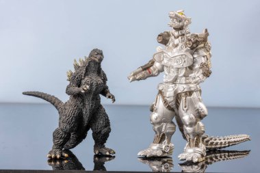 Karşılaşan iki dev kertenkele figürü oyuncak canavarlar. Efsanevi Asyalı canavar maskotu. Yansıyan yüzeydeki plastik yaratıklar. Kopyalama alanı olan kültürel nesne arka planı. Modern David ve Goliath.