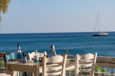 Atina, Yunanistan - 29 Eylül 2021: Tabaklar ve el dezenfektanı şişesiyle hazırlanmış masa. Manzaralı sokak kahvesi, Coronavirus 'tan sonra tekrar açıldı. Doğal arka planda fotokopi alanı ile şişe dezenfekte ediliyor